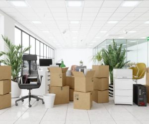 Moving To New Office With Chairs, Cardboard Boxes, Plants, Computers And Other Office Equipments.